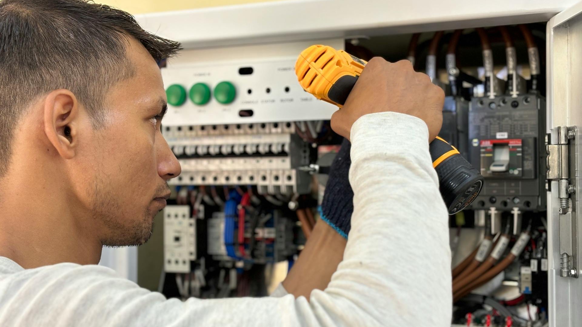 Elektriker im Notdienst arbeitet mit Taschenlampe am Zählerschrank
