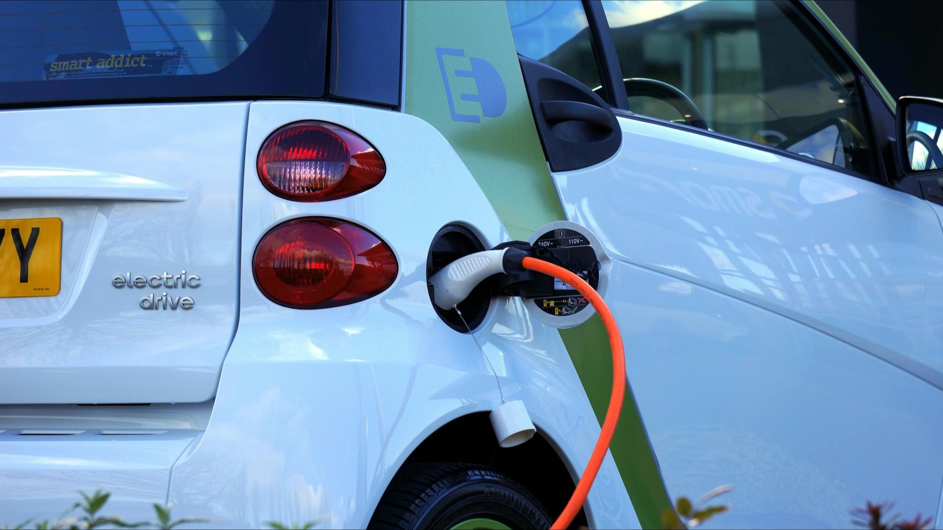 Elektroauto lädt an einer Wallbox mit orangem Ladekabel